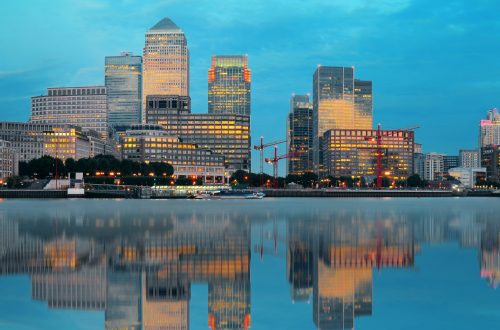 Canary Wharf business district in London at sunset with reflection.
