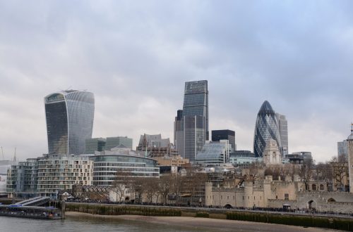 A wide shot of tall glass buildings in London near the lake